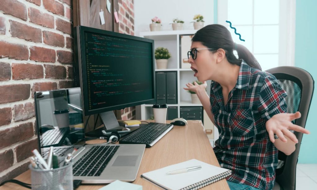 Mulher com face de indignação, olhando para o computador.