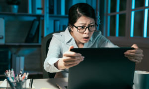 mulher com a face assustada, olhando para o computador.