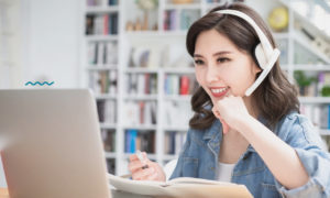 Mulher em frente ao computador. Imagem remete aos estudos on-line.