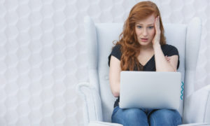 Menina em frente ao computador com expressão de assustada. Imagem remete à preocupação por não ler as Políticas de Privacidade.