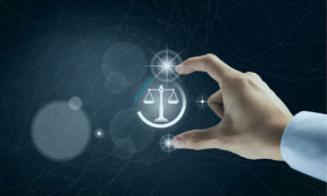 Mão segurando a balança da Justiça em um cenário virtual. Imagem simboliza a LPGD no meio online.