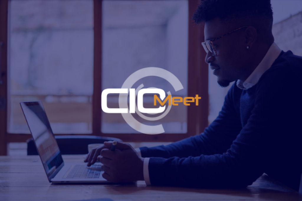 Profissional negro em frente ao computador e a logo do CIO Meet no meio da imagem. Simboliza o CIO Meet 2020 que será online.
