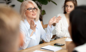 Mulher conversando com outros profissionais em um escritório. Imagem simboliza que a coach está ajudando na carreira dos demais.