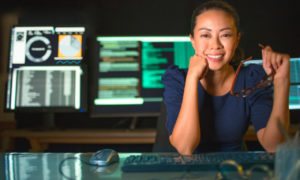 Mulher mexendo em códigos de computadores. Imagem simboliza que ela está trabalhando com a criptografia de dados.
