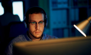 Profissional olhando concentrado para a tela do computador. Imagem simboliza um desenvolvedor java full stack trabalhando.