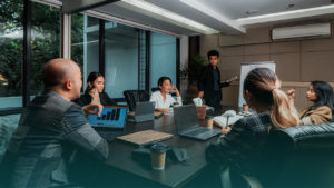 Seis pessoas conversando em sala de reunião. Imagem simboliza que são líderes de TI falando sobre os desafios comuns da área.