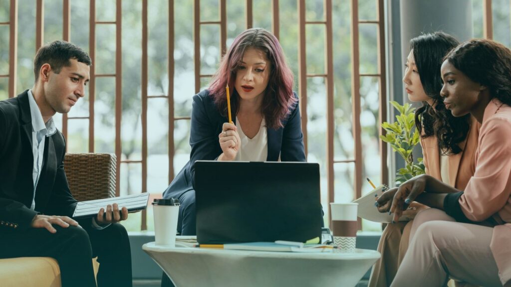 Quatro pessoas conversando em um escritório. Imagem simboliza que são recrutadores falando sobre a contratação de um Scrum Master.