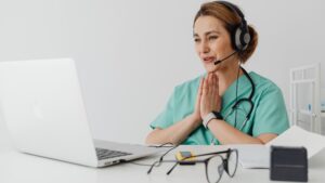 Médica feliz em frente ao computador. Imagem simboliza o atendimento pela telemedicina com ajuda da IA.